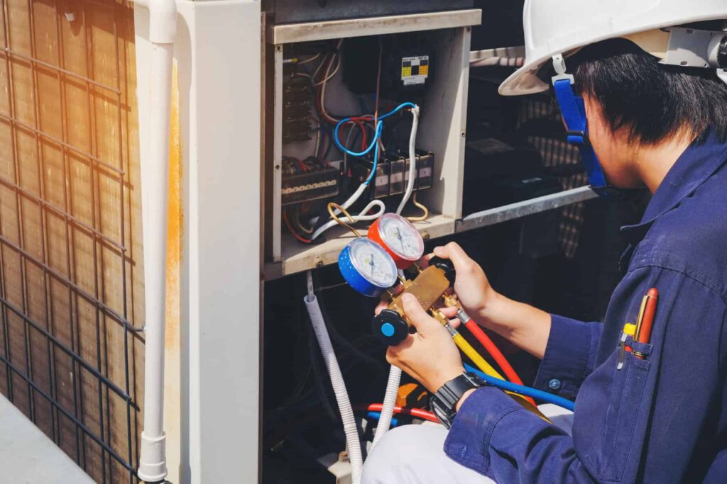 friendly altruistic ac technician holding red and blue gauges during system maintenance check in austin, tx