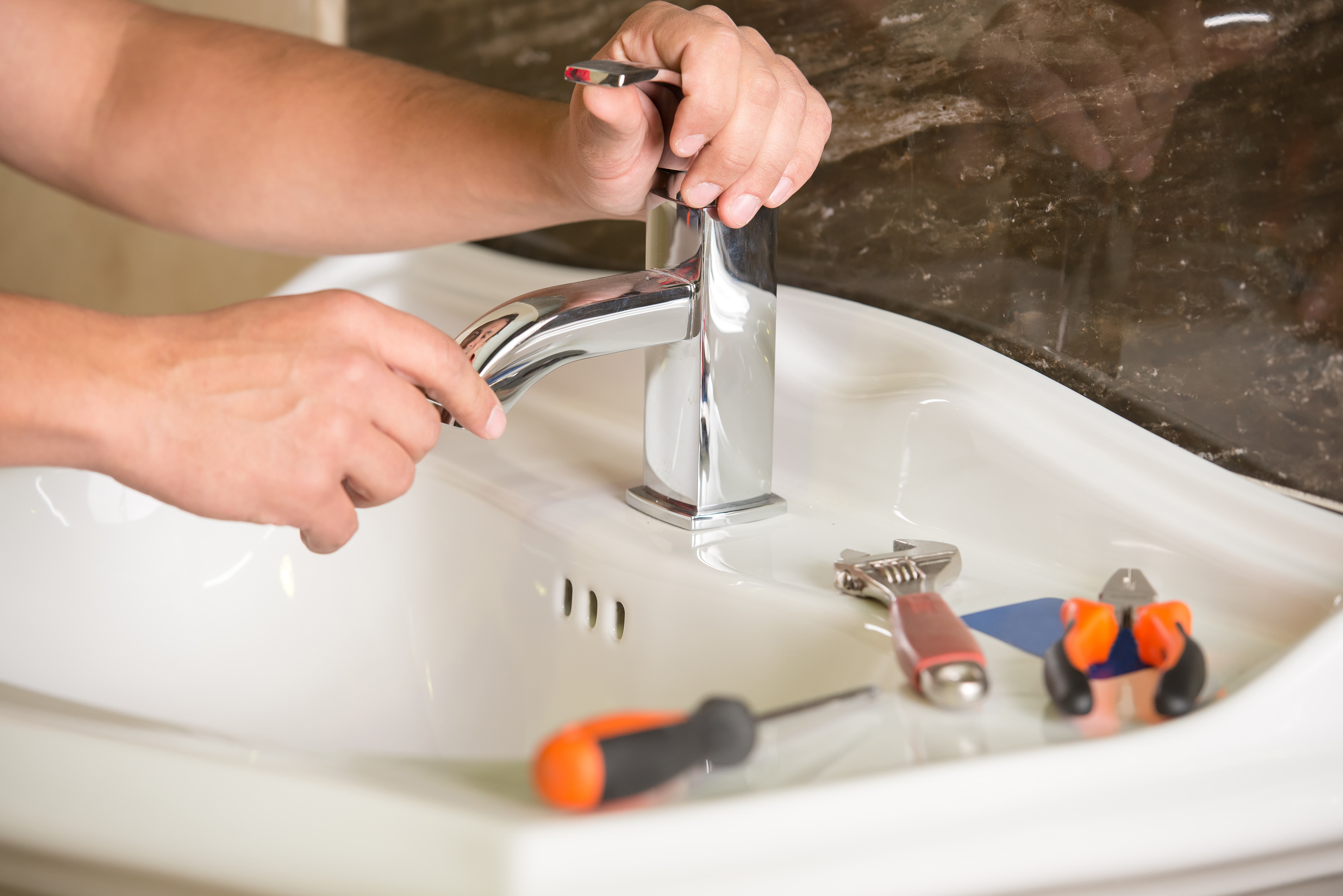 closeup of a plumber installing a new faucet on a sink in a home