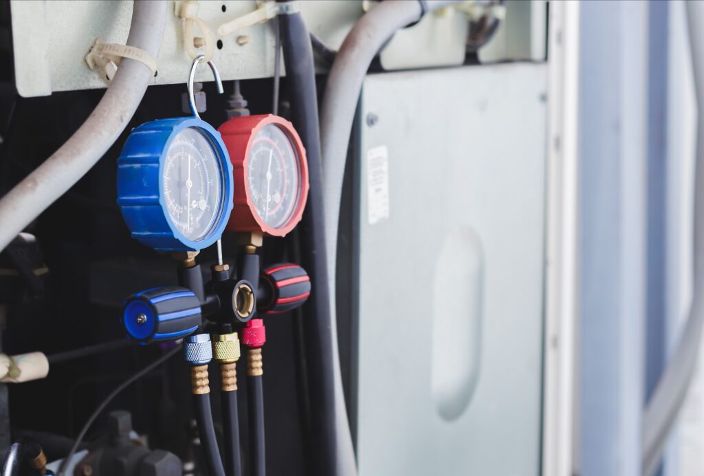 closeup of refrigerant pressure reader hooked to an outdoor hvac unit